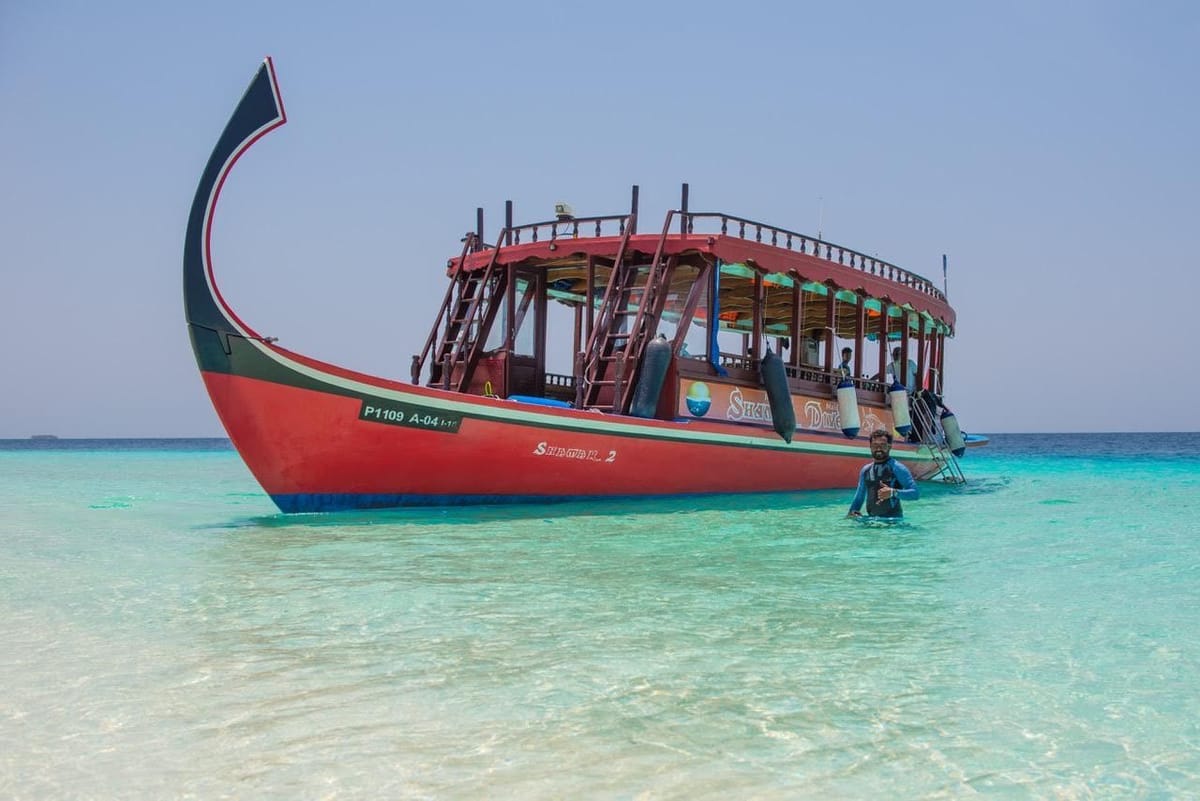 The red dhoni off a sandbank in turquoise water