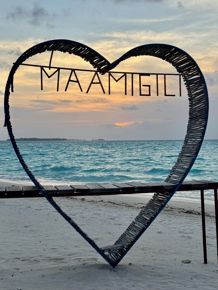 A heart-shaped frame spelling Maamigili on the beach
