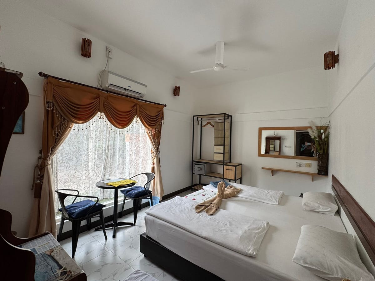 Bright ground-floor room with a king-size bed, a tiled floor and a table with two chairs by the window