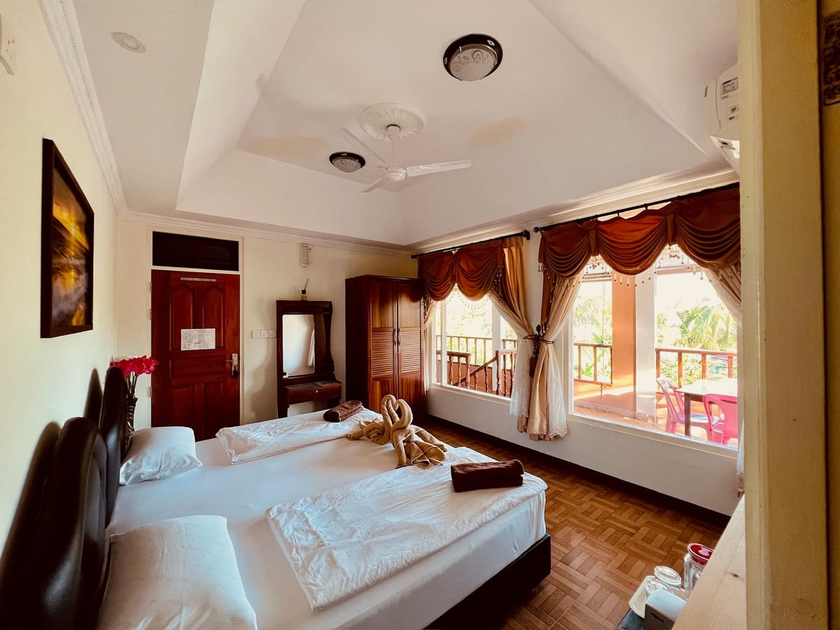 Corner room with wide windows, the terrace with a table and chairs beyond