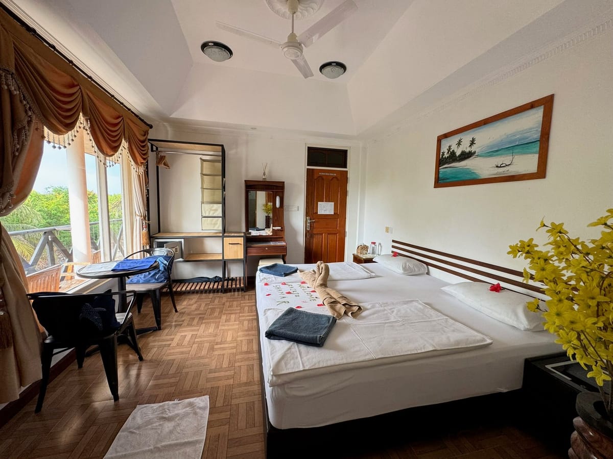 Double room with the balcony door open and a framed sea print above the bed